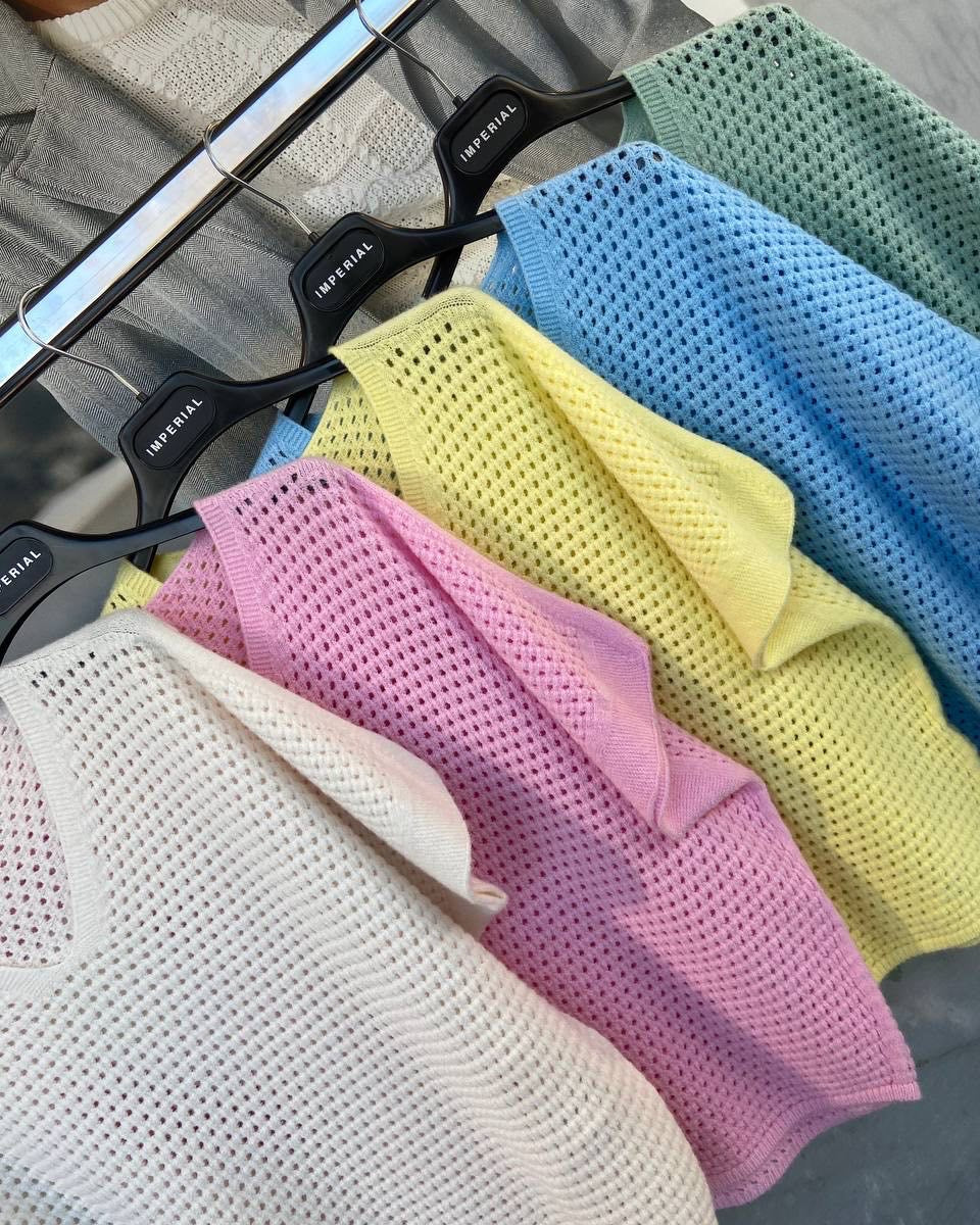 A collection of sweaters displayed on hangers in various colors including blue, yellow, pink, gray, and green.