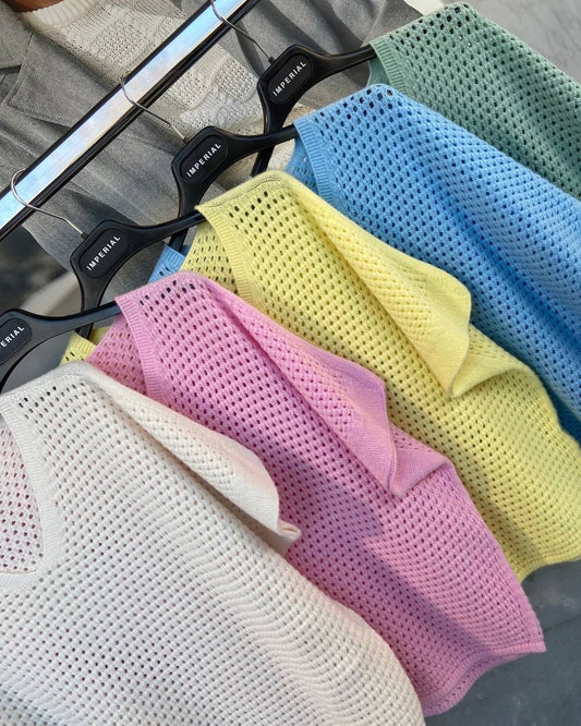 A collection of sweaters displayed on hangers in various colors including blue, yellow, pink, gray, and green.