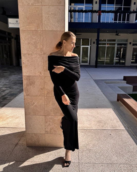 A person standing in a semi-circle pose wearing an off-shoulder black dress.