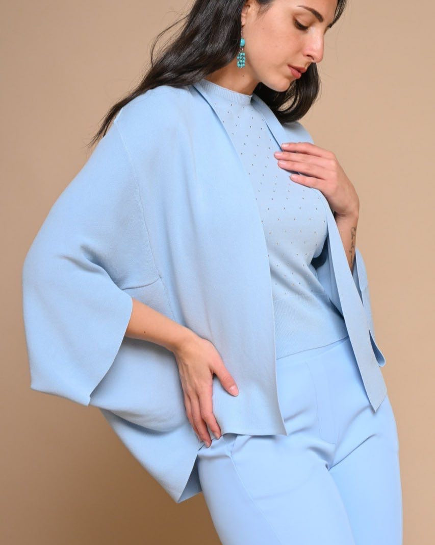 A person wearing a light blue blazer with a round neckline and long sleeves, paired with a matching light blue top and trousers.