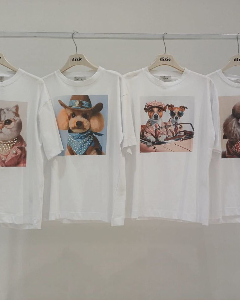 A selection of white t-shirts with different puppy images printed on them, displayed on hangers.