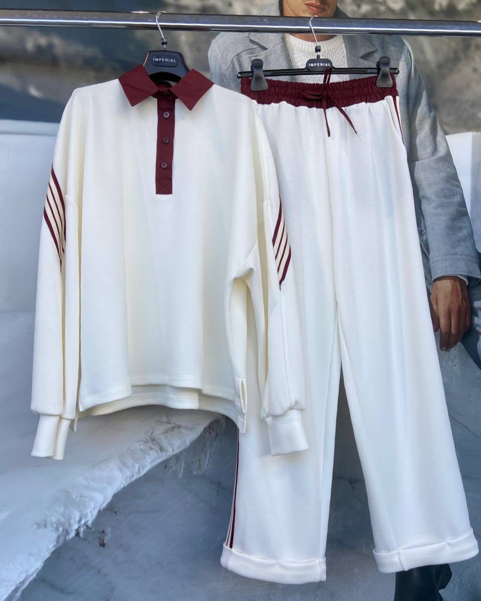 A set of white golf pants and a matching long-sleeved golf shirt with red accents displayed on hangers.