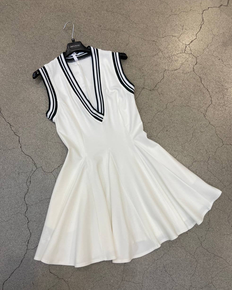 A sleeveless white golf dress with black accents and a pleated skirt, displayed on a hanger.