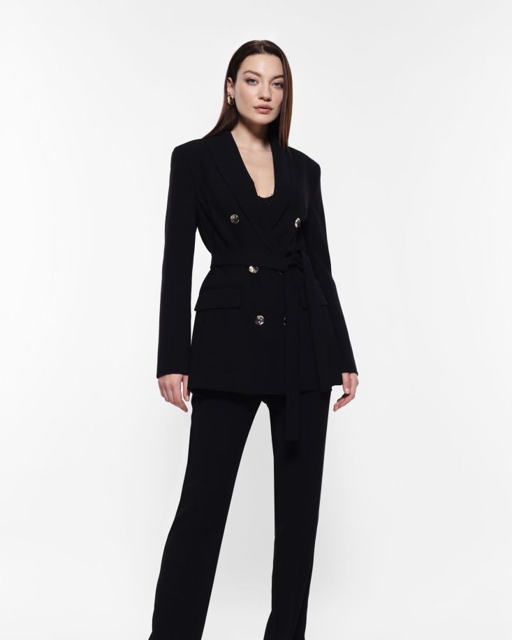 A woman posing in a black suit jacket with double-breasted buttons.