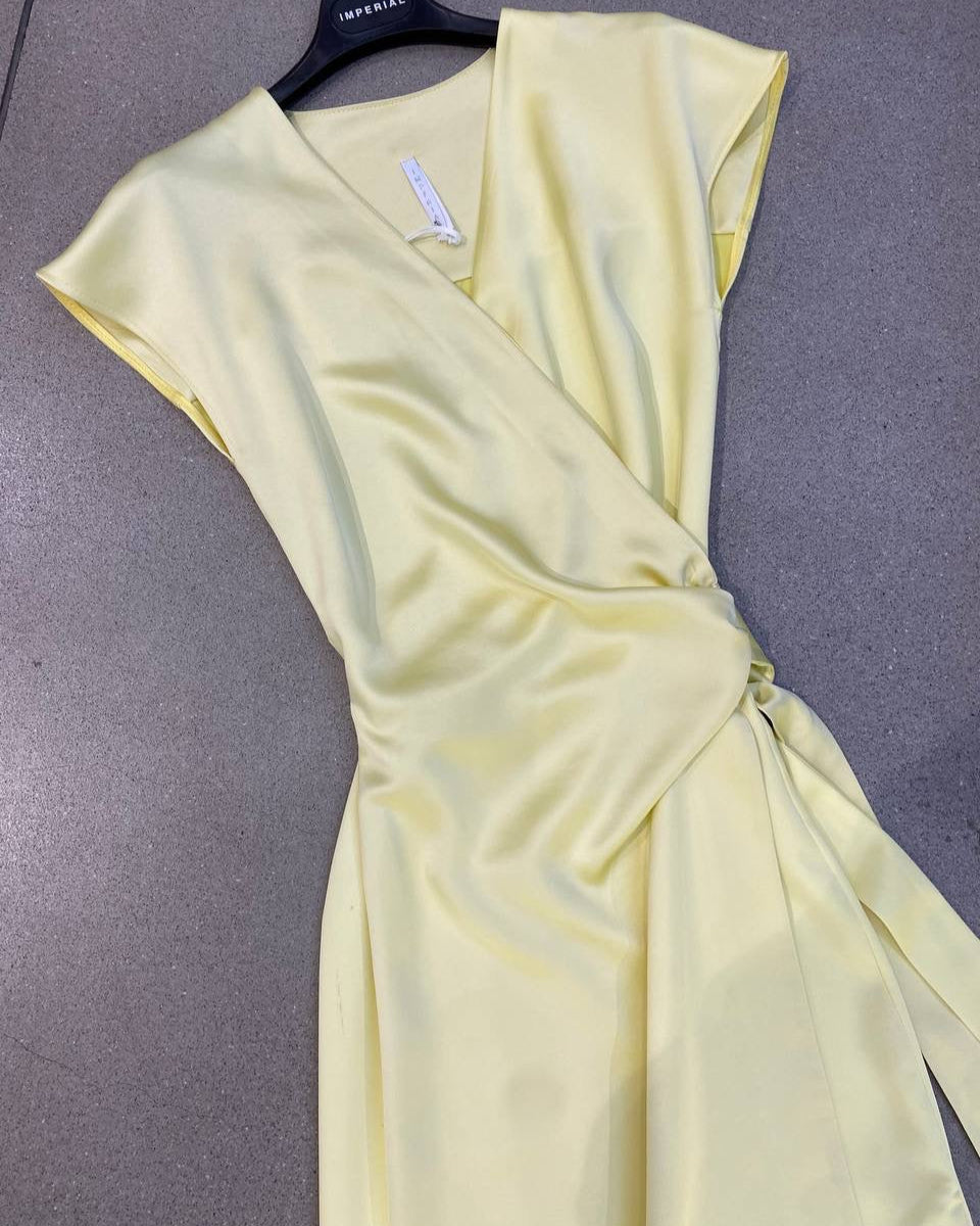 A yellow dress with a V-neckline, short sleeves, and a tie waist hanging on a hanger against a plain background.
