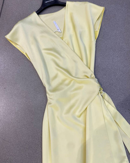 A yellow dress with a V-neckline, short sleeves, and a tie waist hanging on a hanger against a plain background.