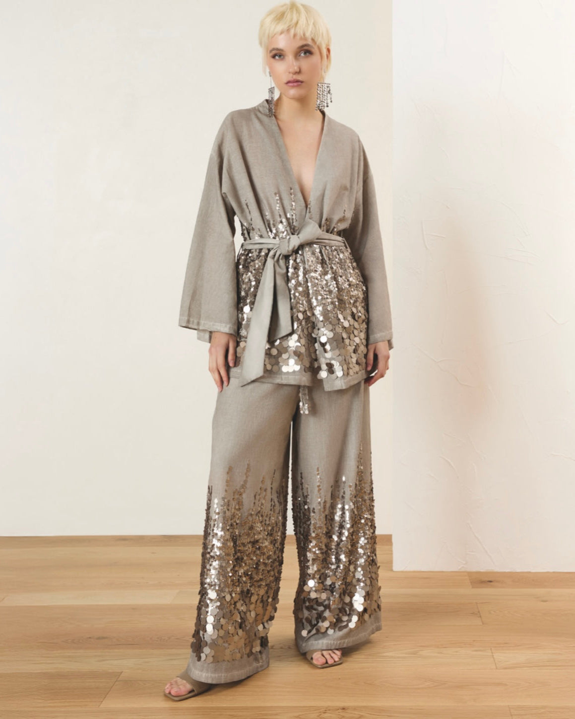 Person wearing a gray sequined outfit against a plain background