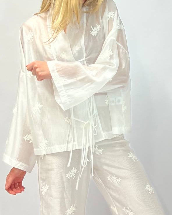Person wearing a white floral pajama set against a white background