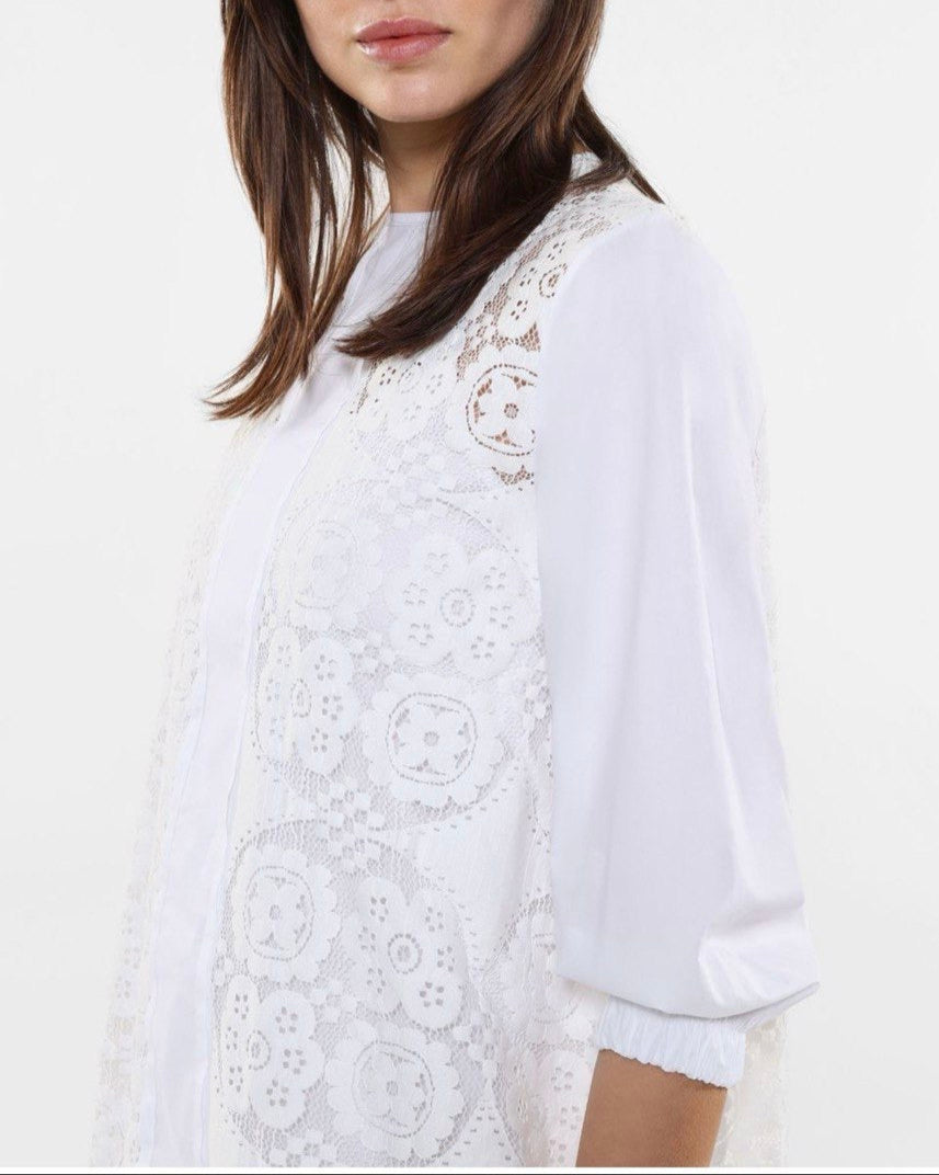 This image features a stylish white dress known as "Dress Twiggy," modeled by a woman wearing sunglasses. The dress showcases intricate lace detailing and a flowing silhouette, emphasizing elegance and contemporary fashion.