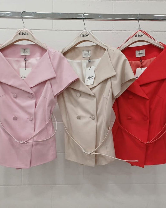Three jackets hanging on a rack, next to each other, in pink, beige, and red colors.