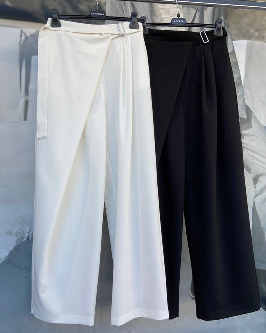Two pairs of pants, one white and one black, displayed on hangers against a gray background.