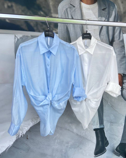 Two shirts, one light blue and one white, hanging on a rack.