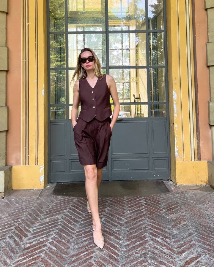 Woman in a sleeveless dress standing in front of a large window with yellow frame.