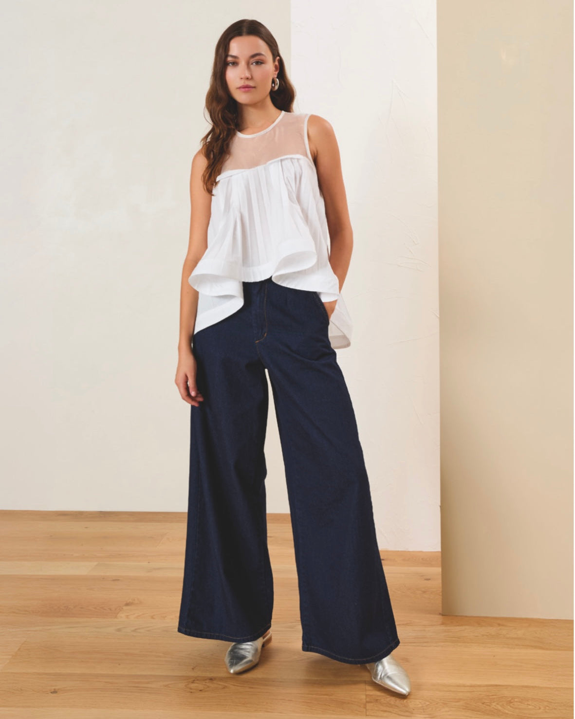 Woman in white top and navy pants standing indoors