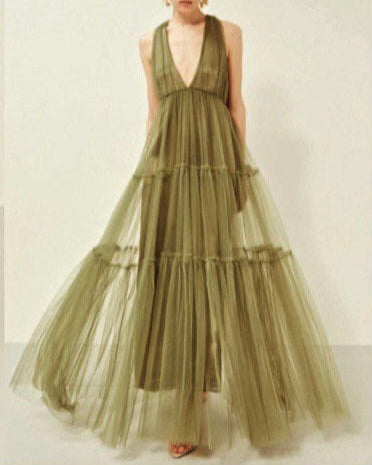Woman wearing a green tiered dress against a plain background
