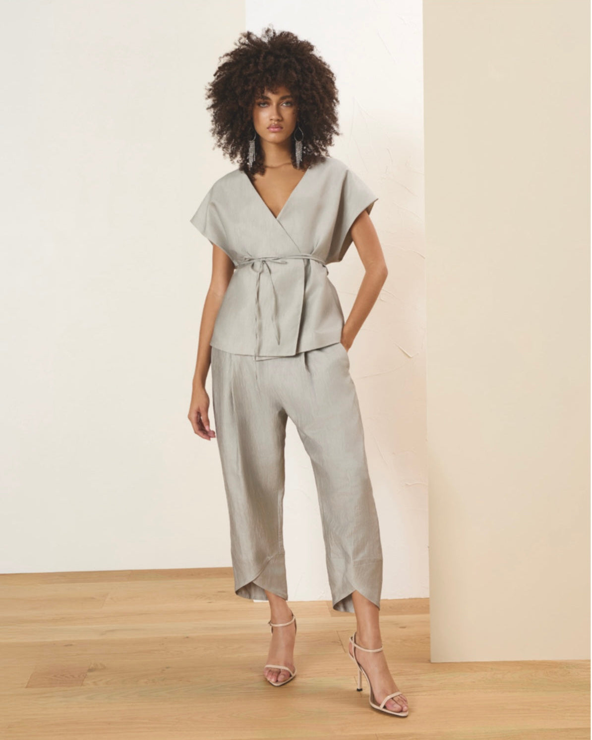 Woman wearing a light gray outfit in a minimalistic setting