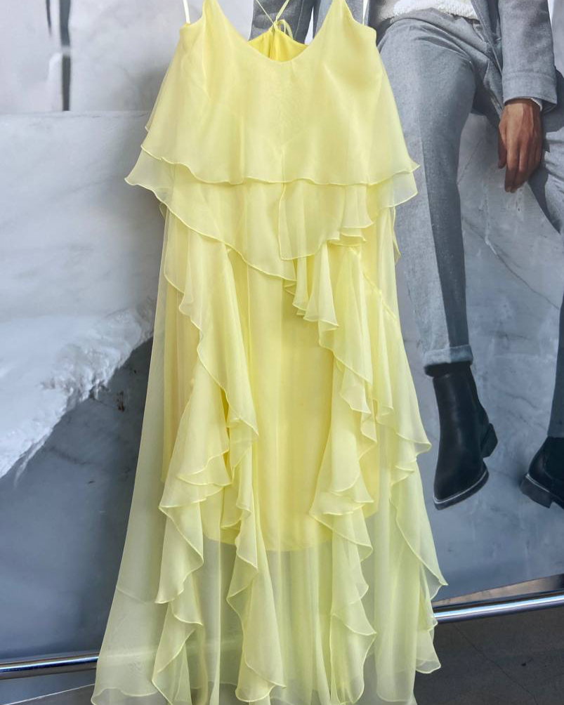 Yellow ruffled dress on a hanger with a blurred background