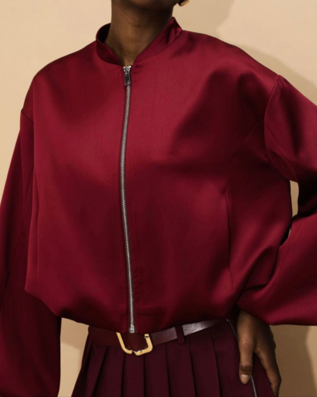 A person wearing a red bomber jacket with a visible zipper.